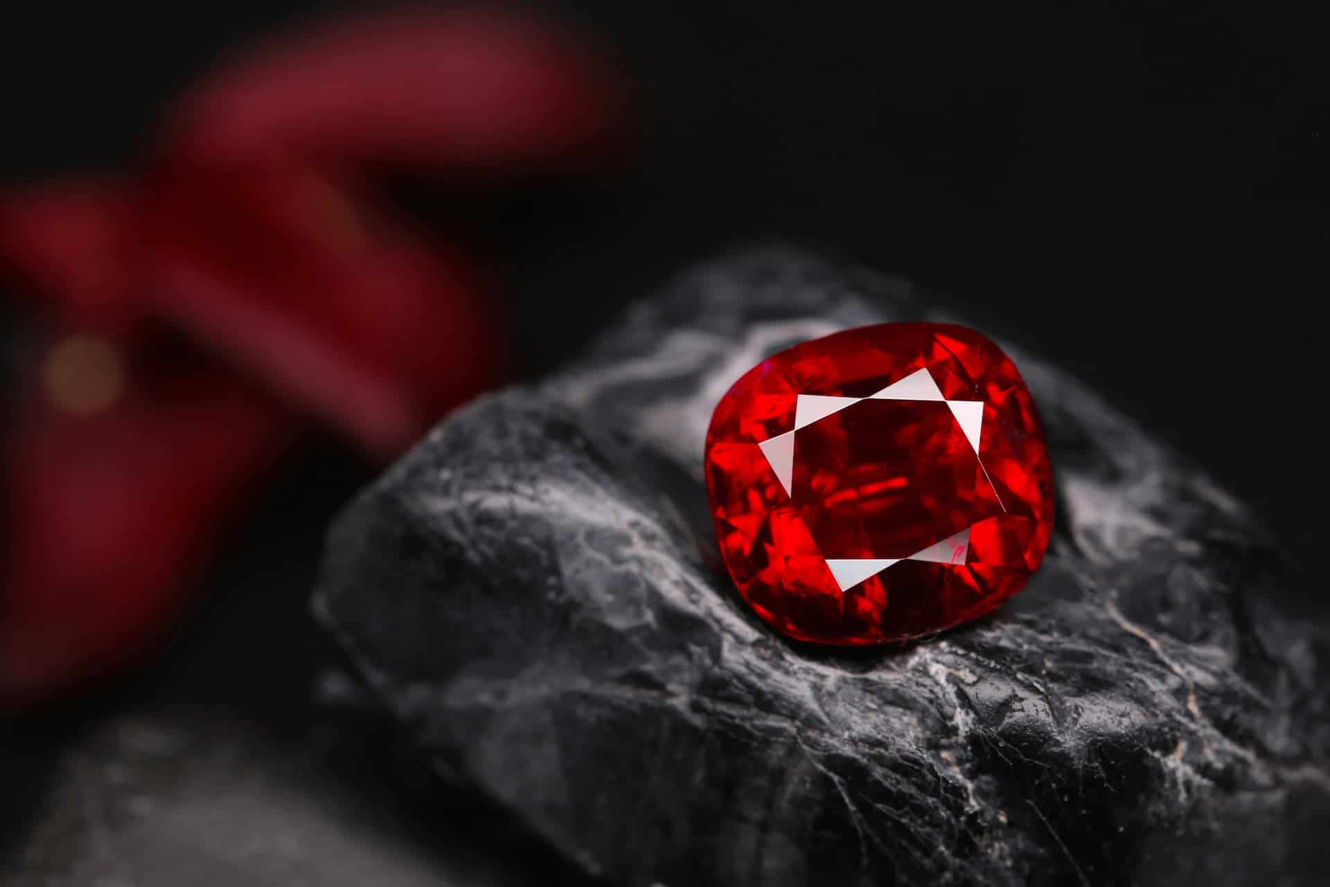 Close up of beautifully lit sparkling red gemstone set on a black stone.