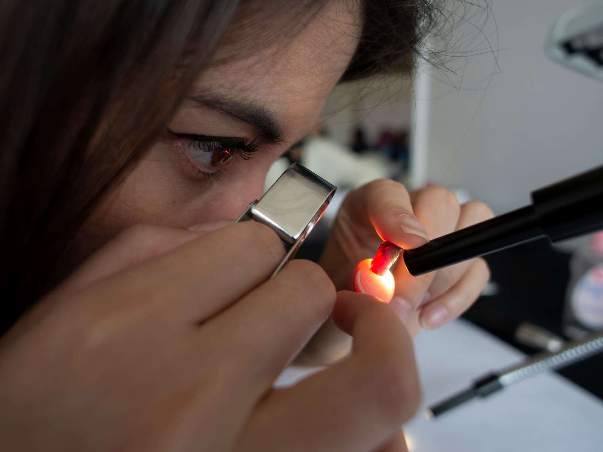 Billie Hughes examining a ruby through a jewelry loupe.